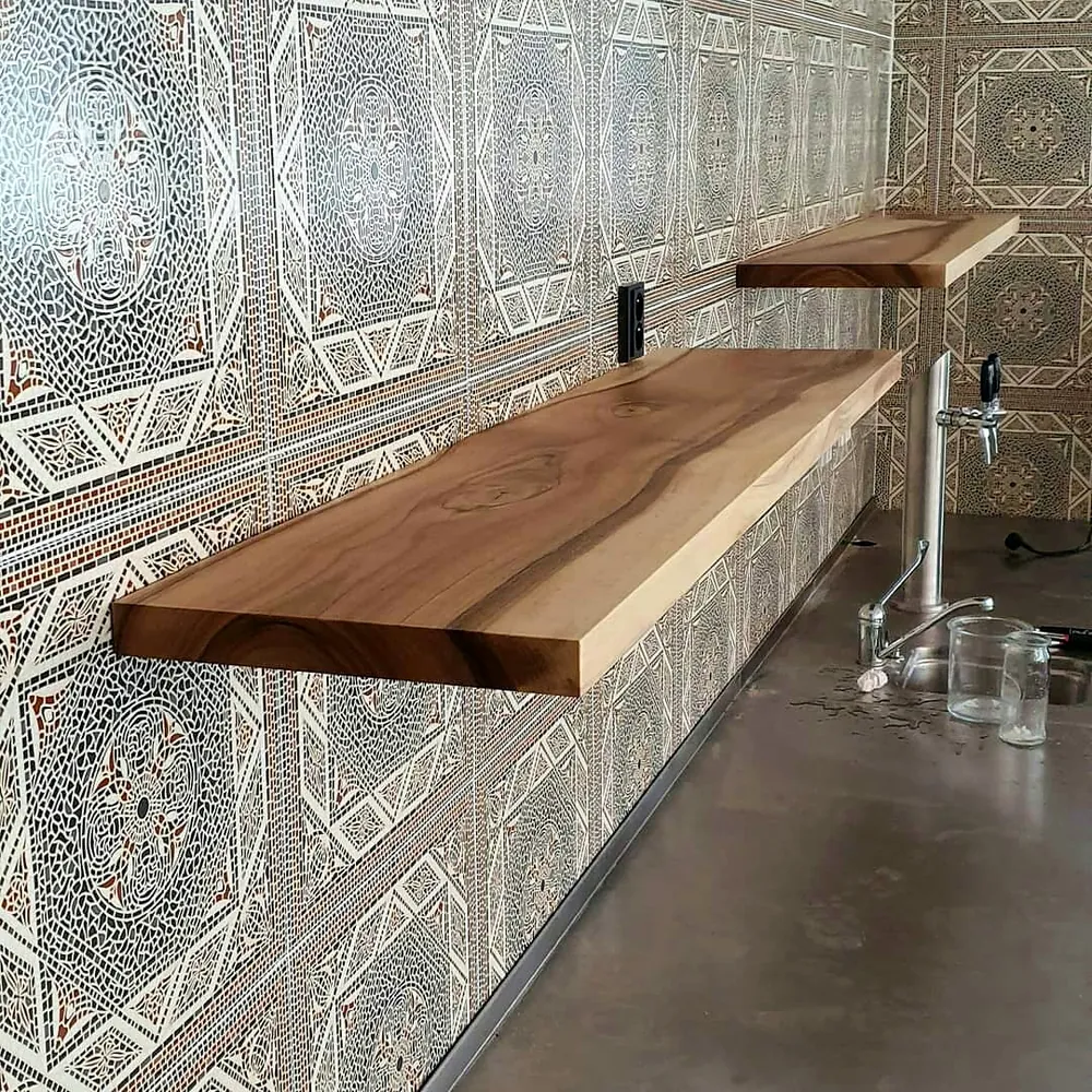Ořechové police připevněné na zdi s ornamentálním obkladem v restauraci